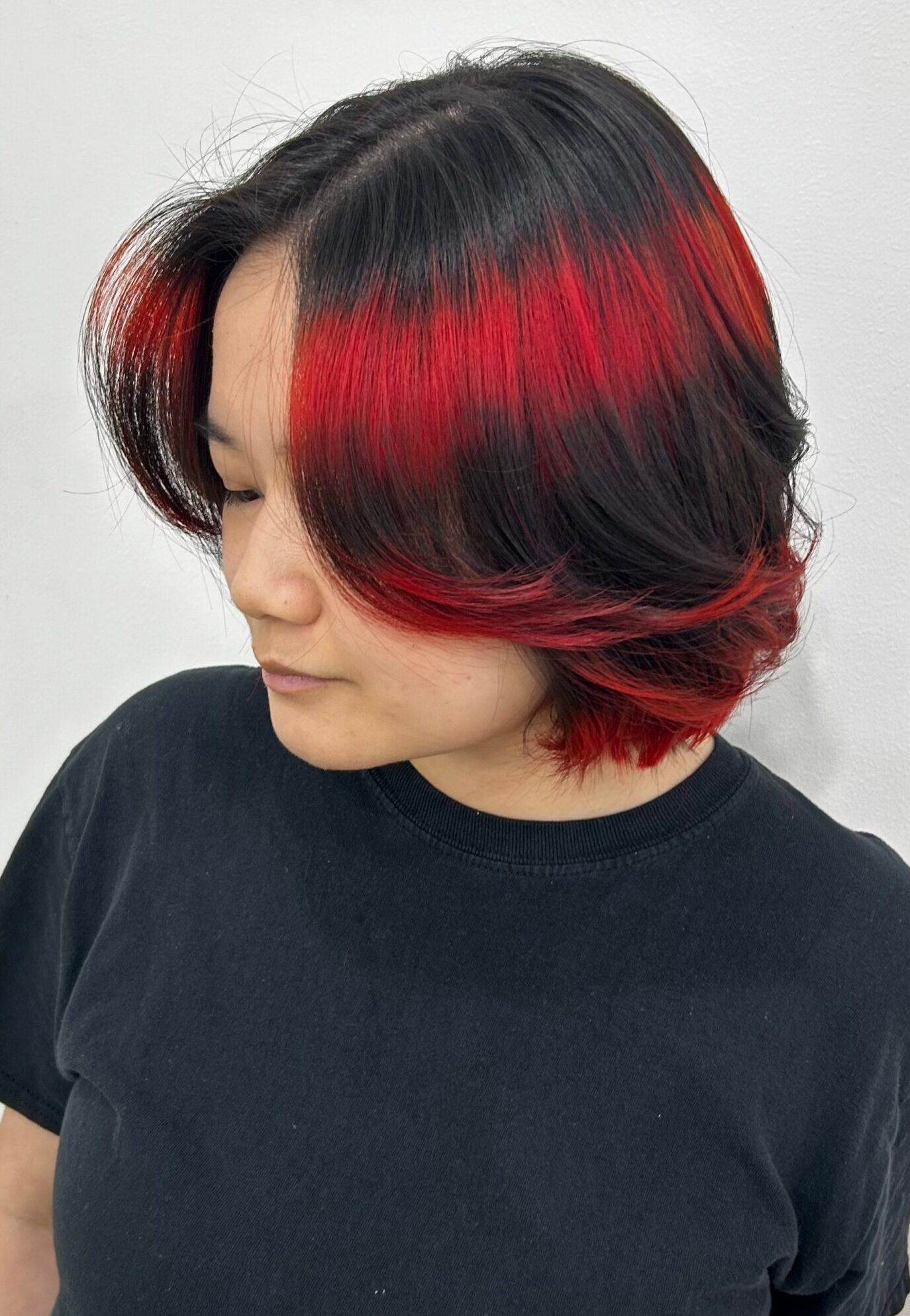 A high-contrast 2026 hair trend featuring a black base with bold red horizontal stripes and vibrant red dip-dyed ends, styled at Assort Osaka.