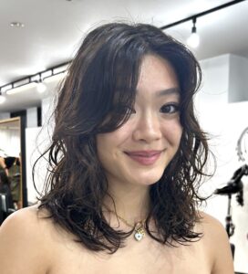 Close-up of defined, springy curls styled with a wet-look finish at Assort Osaka, inspired by editorial wolf-cut textures.